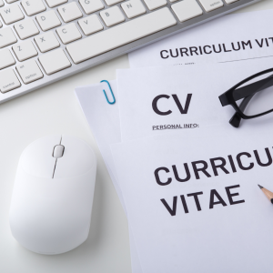 Photo of a printed CV with a mouse, keyboard, and glasses