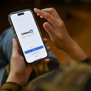 Photo of a person holding a phone with LinkedIn on the screen.